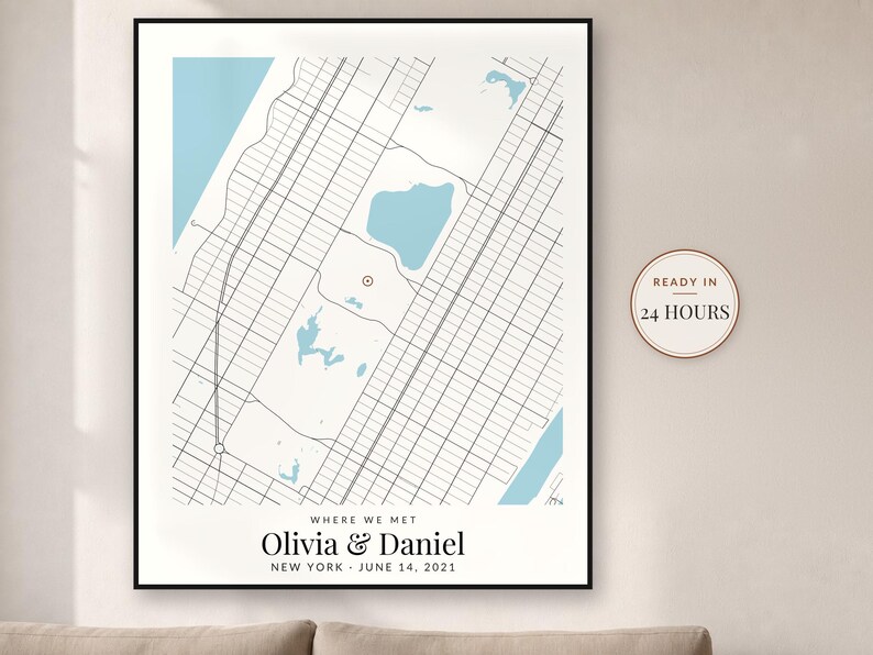 May include: A framed map print featuring a grid of city streets, light blue water bodies, and a red location marker. Text reads: WHERE WE MET, Olivia & Daniel, NEW YORK, JUNE 14, 2021. A circular badge on the right states: READY IN 24 HOURS.