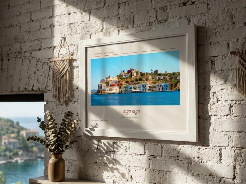 May include: A framed horizontal wall art print featuring a vibrant photograph of the Greek island Kastellorizo with colorful buildings along the water. The print includes the text Kastellorizo, Greece at the top and the phrase siga siga at the bottom.