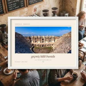 Puede incluir: Una impresi&oacute;n horizontal enmarcada que presenta una fotograf&iacute;a panor&aacute;mica del antiguo teatro de Hier&aacute;polis en Pamukkale, Turqu&iacute;a. El texto dice HIERAPOLIS - PAMUKKALE, ge&ccedil;miş h&acirc;l&acirc; burada y THE PAST IS STILL HERE, con cr&eacute;dito fotogr&aacute;fico a Ahmet Cidar.