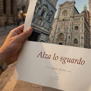 Op de afbeelding: Een rechthoekige papieren afdruk met een gedetailleerde architectuurfoto van de gevel van de kathedraal van Florence. De tekst Alza lo sguardo en BAŞINI KALDIR is in donkerbruine inkt gedrukt op het onderste deel van het cr&egrave;mekleurige papier.