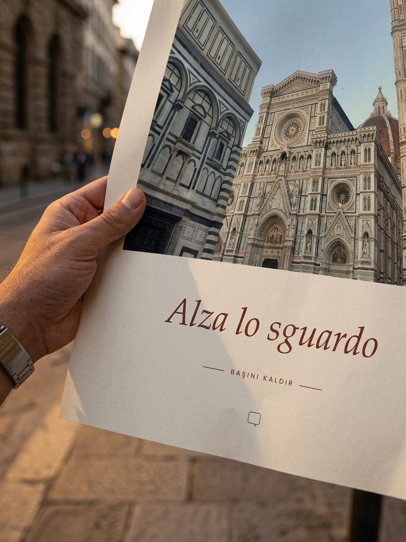 Op de afbeelding: Een rechthoekige papieren afdruk met een gedetailleerde architectuurfoto van de gevel van de kathedraal van Florence. De tekst Alza lo sguardo en BAŞINI KALDIR is in donkerbruine inkt gedrukt op het onderste deel van het cr&egrave;mekleurige papier.