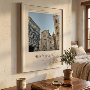 Puede incluir: Una l&aacute;mina de arte enmarcada que presenta una fotograf&iacute;a de la Piazza del Duomo en Florencia, Italia. La impresi&oacute;n incluye el texto 'PIAZZA DEL DUOMO FIRENZE' en la parte superior y 'Alza lo sguardo' con 'BASINI VALDIE' bajo la imagen en un marco blanco.