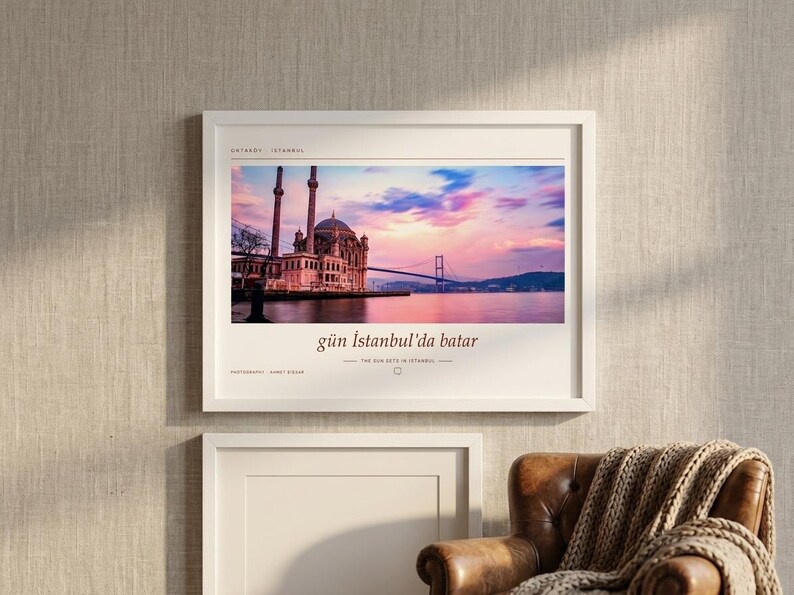 May include: A framed horizontal wall art print featuring a photograph of the Ortak&ouml;y Mosque in Istanbul at sunset with a pink and blue sky, the Bosphorus Bridge, and the text "g&uuml;n İstanbul'da batar" printed in a serif font below the image.
