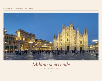 May include: A photograph of the Duomo di Milano in Piazza del Duomo, Milan, at twilight. The cathedral is illuminated against a deep blue sky. Text at the top reads PIAZZA DEL DUOMO MILANO and at the bottom reads Milano si accende MILAN LIGHTS UP.