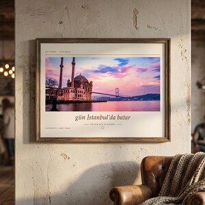 May include: A framed horizontal wall art print featuring a photograph of the Ortak&ouml;y Mosque in Istanbul at sunset, with the Bosphorus Bridge in the background. The print includes the text "g&uuml;n İstanbul'da batar" and "THE SUN SETS IN ISTANBUL".
