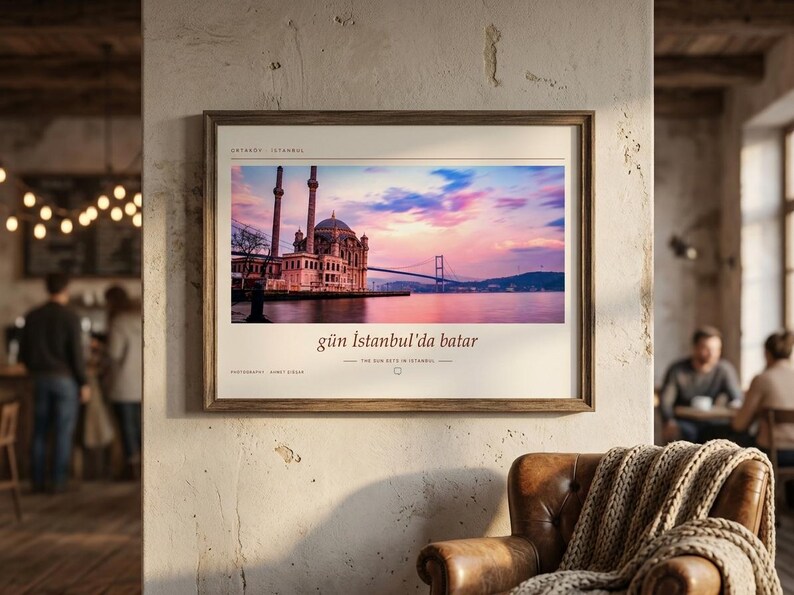 May include: A framed horizontal wall art print featuring a photograph of the Ortak&ouml;y Mosque in Istanbul at sunset, with the Bosphorus Bridge in the background. The print includes the text "g&uuml;n İstanbul'da batar" and "THE SUN SETS IN ISTANBUL".
