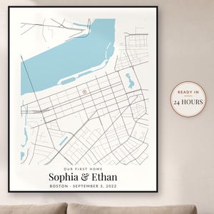 May include: A framed map print featuring a light blue body of water and black street lines. The text reads: OUR FIRST HOME, Sophia & Ethan, BOSTON - SEPTEMBER 3, 2022. A circular badge on the right side displays the text: READY IN 24 HOURS.
