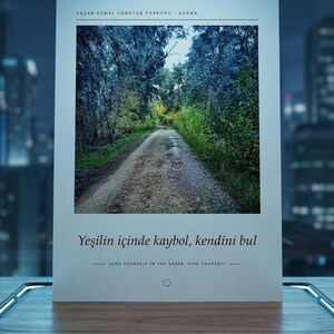 Puede incluir: Un p&oacute;ster rectangular con una fotograf&iacute;a de un camino de tierra que serpentea a trav&eacute;s de un bosque denso. El texto en la parte superior dice YAŞAR KEMAL Y&Uuml;R&Uuml;Y&Uuml;Ş PARKURU - ADANA. Debajo de la imagen, el texto dice Yeşilin i&ccedil;inde kaybol, kendini bul y LOSE YOURSELF IN THE GREEN, FIND YOURSELF.