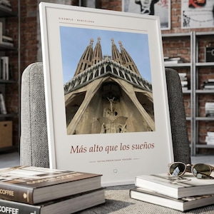 K&ouml;nnte beinhalten: Ein wei&szlig; gerahmter Kunstdruck mit einer Froschperspektive der Sagrada Familia in Barcelona. Der Text EIXAMPLE BARCELONA steht oben, w&auml;hrend der Satz M&aacute;s alto que los sue&ntilde;os und HAYALLERDEN DANA Y&Uuml;KSEĞE darunter aufgedruckt ist.