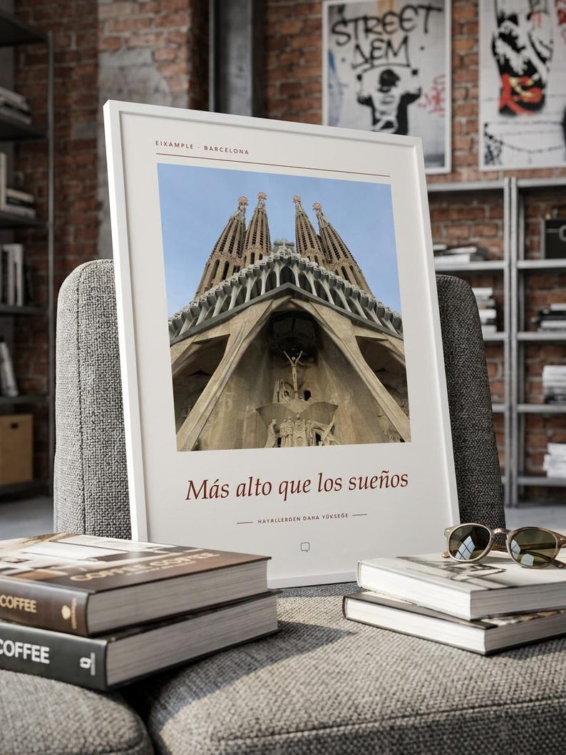 K&ouml;nnte beinhalten: Ein wei&szlig; gerahmter Kunstdruck mit einer Froschperspektive der Sagrada Familia in Barcelona. Der Text EIXAMPLE BARCELONA steht oben, w&auml;hrend der Satz M&aacute;s alto que los sue&ntilde;os und HAYALLERDEN DANA Y&Uuml;KSEĞE darunter aufgedruckt ist.