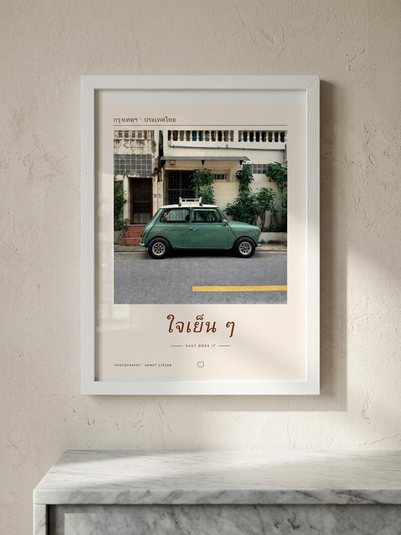 Pode incluir: Uma impress&atilde;o art&iacute;stica emoldurada com a fotografia de um carro antigo verde-s&aacute;lvia estacionado numa rua em frente a um edif&iacute;cio. A impress&atilde;o inclui texto em tailand&ecirc;s, a frase em ingl&ecirc;s "EASY DOES IT" e "PHOTOGRAPHY AHMET CIGSAR."