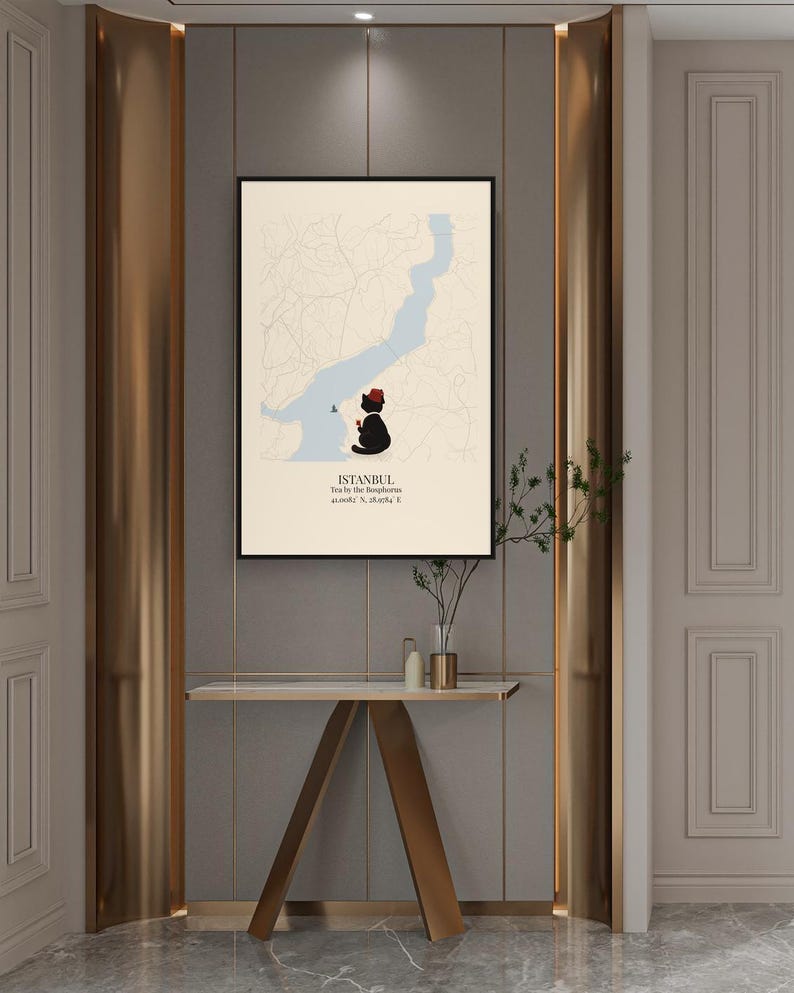 May include: A framed wall art print featuring a cream-colored map of Istanbul with a light blue Bosphorus strait. A black cat wearing a red fez sits on the shore, holding a small red tea glass. Text reads: ISTANBUL, Tea by the Bosphorus, 41.0082&deg; N, 28.9784&deg; E.