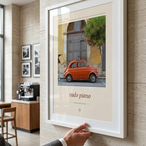 Może przedstawiać: Oprawiony wydruk artystyczny przedstawiający fotografię pomarańczowego zabytkowego samochodu zaparkowanego przed ciemnymi drewnianymi drzwiami na Sycylii we Włoszech. Wydruk zawiera tekst "SICILIA ITALIA" na g&oacute;rze oraz "vado piano" z "YAVAŞ GİDİYORUM" poniżej.