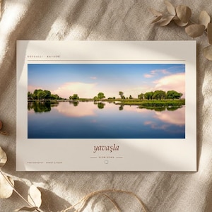Pode incluir: Uma impress&atilde;o retangular com uma fotografia de paisagem de um lago calmo refletindo um c&eacute;u azul com nuvens suaves e &aacute;rvores verdes. O texto SOYSALLI KAYSERI aparece no topo, enquanto yavaşla e SLOW DOWN est&atilde;o impressos abaixo da imagem.