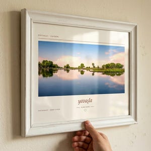Pode incluir: Uma fotografia de paisagem numa moldura branca desgastada mostrando um lago calmo que reflete &aacute;rvores e um c&eacute;u ao p&ocirc;r do sol. A impress&atilde;o inclui o texto SOYSALLI - KAYSERI, yavaşla, SLOW DOWN e PHOTOGRAPHY AHMET ELCAR em fonte clara.