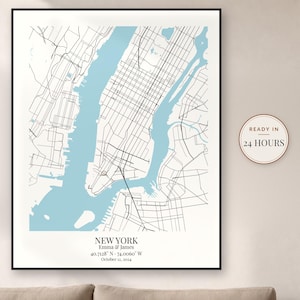 May include: A framed map print of New York City featuring black street lines on a white background with light blue water. The text reads NEW YORK, Emma & James, 40.7128 N - 74.0060 W, October 12, 2024. A circular badge states READY IN 24 HOURS.