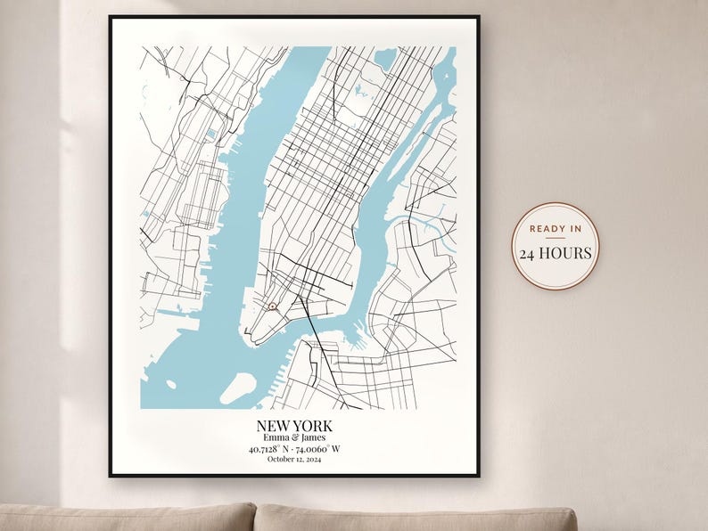 May include: A framed map print of New York City featuring black street lines on a white background with light blue water. The text reads NEW YORK, Emma & James, 40.7128 N - 74.0060 W, October 12, 2024. A circular badge states READY IN 24 HOURS.