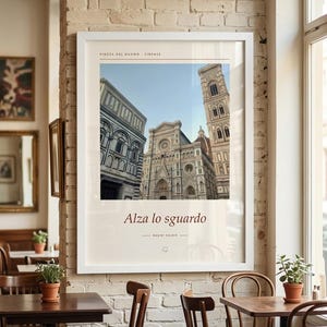 Puede incluir: Una impresi&oacute;n de arte enmarcada en blanco que presenta una fotograf&iacute;a de la Piazza del Duomo en Florencia, Italia. La impresi&oacute;n incluye el texto "PIAZZA DEL DUOMO FIRENZE" en la parte superior y "Alza lo sguardo" con "BASINI KALDIR" debajo.