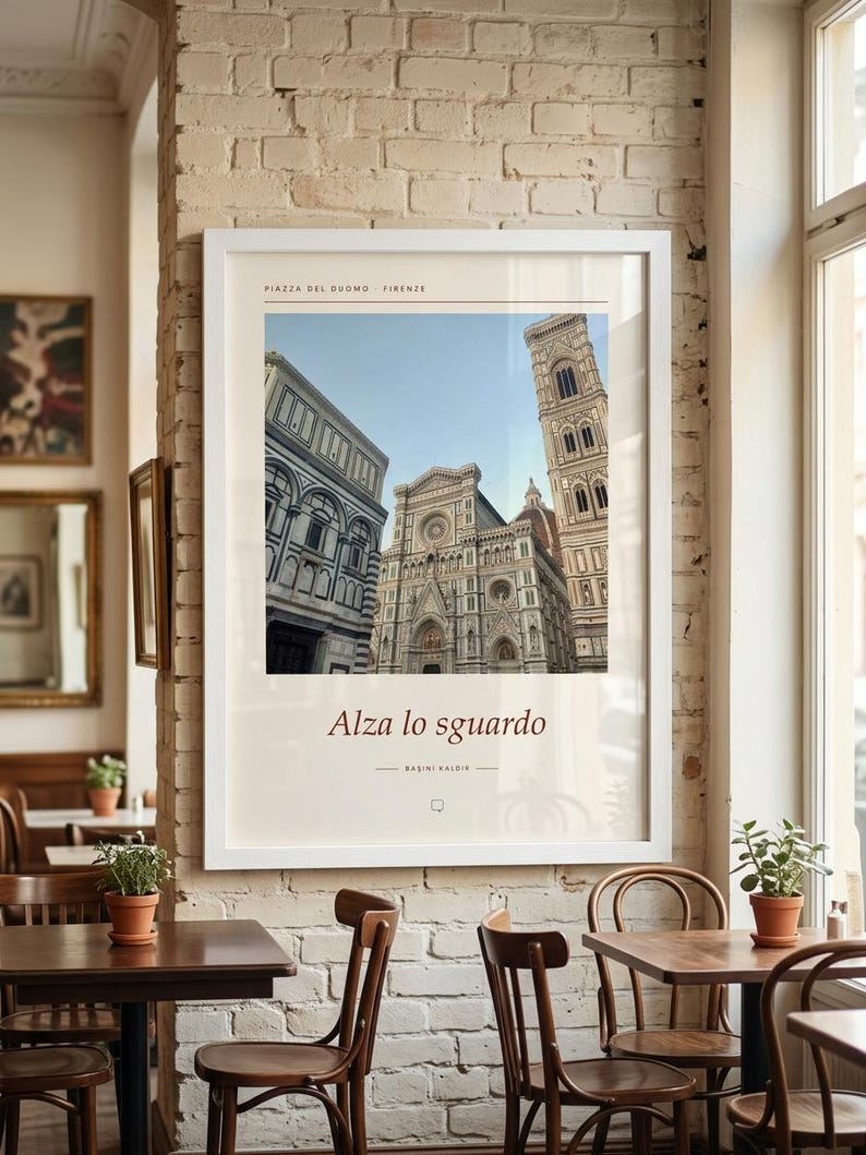 Puede incluir: Una impresi&oacute;n de arte enmarcada en blanco que presenta una fotograf&iacute;a de la Piazza del Duomo en Florencia, Italia. La impresi&oacute;n incluye el texto "PIAZZA DEL DUOMO FIRENZE" en la parte superior y "Alza lo sguardo" con "BASINI KALDIR" debajo.