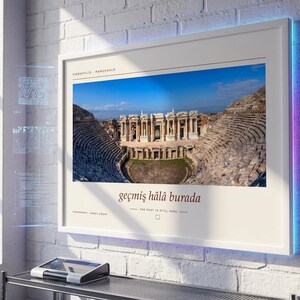 Puede incluir: Una l&aacute;mina de pared enmarcada con una fotograf&iacute;a del teatro antiguo de Hier&aacute;polis en Pamukkale. La l&aacute;mina incluye el texto Hierapolis Pamukkale, la frase ge&ccedil;miş h&acirc;l&acirc; burada y la traducci&oacute;n al ingl&eacute;s The past is still here.