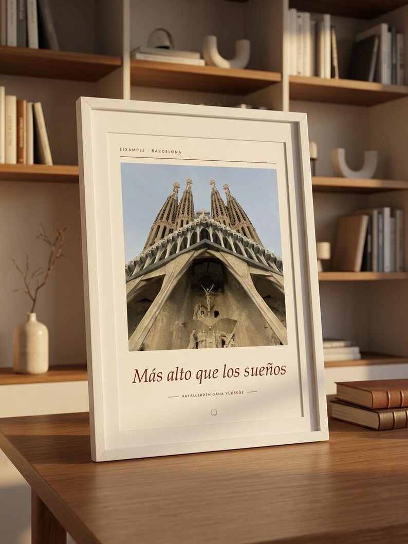 K&ouml;nnte beinhalten: Ein wei&szlig; gerahmter Kunstdruck mit einer Froschperspektive der Sagrada Familia in Barcelona. Oben steht der Text EIXAMPLE BARCELONA, w&auml;hrend darunter die S&auml;tze M&aacute;s alto que los sue&ntilde;os und HAYALLERDEN DAHA Y&Uuml;KSEĞE zu sehen sind.