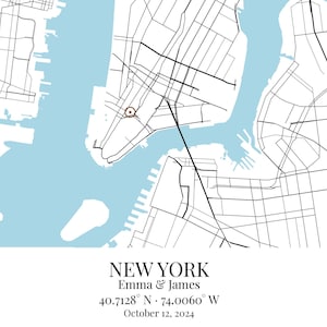 May include: A map print of New York featuring black street lines on a white background with light blue water areas. A small brown circle marks a location. Text reads: NEW YORK, Emma & James, 40.7128&deg; N &middot; 74.0060&deg; W, October 12, 2024.