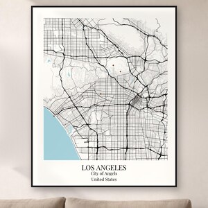 May include: A framed wall art print featuring a black and white street map of Los Angeles, California. The map displays a grid of roads, a light blue coastline, and the text LOS ANGELES, City of Angels, United States at the bottom.