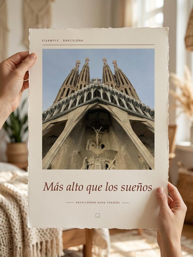 K&ouml;nnte beinhalten: Ein rechteckiger Kunstdruck auf strukturiertem cremefarbenem Papier mit einer Froschperspektiven-Fotografie der Sagrada Familia in Barcelona. Oben steht der Text EIXAMPLE BARCELONA, darunter der Satz M&aacute;s alto que los sue&ntilde;os.
