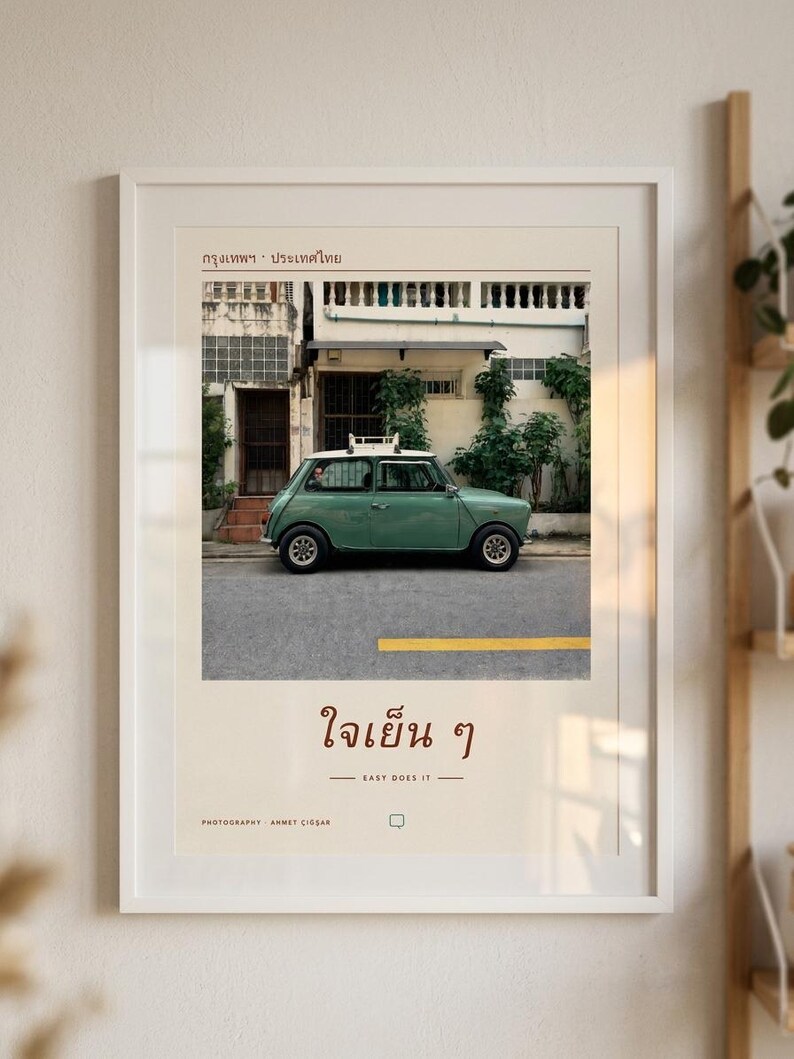 Pode incluir: Uma impress&atilde;o art&iacute;stica emoldurada com a fotografia de um carro vintage verde-s&aacute;lvia estacionado numa rua em frente a um edif&iacute;cio. A impress&atilde;o inclui texto tailand&ecirc;s no topo, a frase "ใจเย็น ๆ" no centro e o texto "EASY DOES IT".