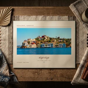 May include: A rectangular book with a cream-colored cover featuring a photograph of a coastal town with colorful buildings by the blue sea. The text reads Castellorizo, Yunanistan, siga siga, and photography: Ahmet Fidan in black serif font.