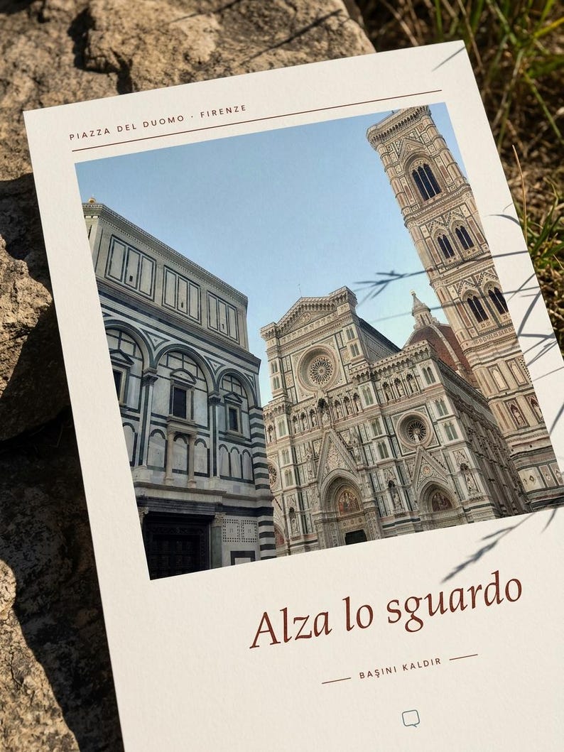 Op de afbeelding: Een rechthoekige print met een foto van de Piazza del Duomo in Florence, Itali&euml;, met de tekst Piazza del Duomo - Firenze bovenaan en Alza lo sguardo en BAŞINI KALDIR in bruine letters onder de afbeelding van de kathedraal.