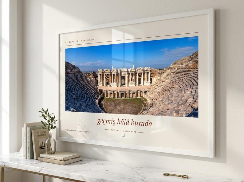 Puede incluir: Una impresi&oacute;n de arte mural horizontal enmarcada que presenta una fotograf&iacute;a del teatro antiguo de Hier&aacute;polis en Pamukkale. La impresi&oacute;n incluye el texto Hierapolis Pamukkale, la frase ge&ccedil;miş h&acirc;l&acirc; burada y la traducci&oacute;n The past is still here.