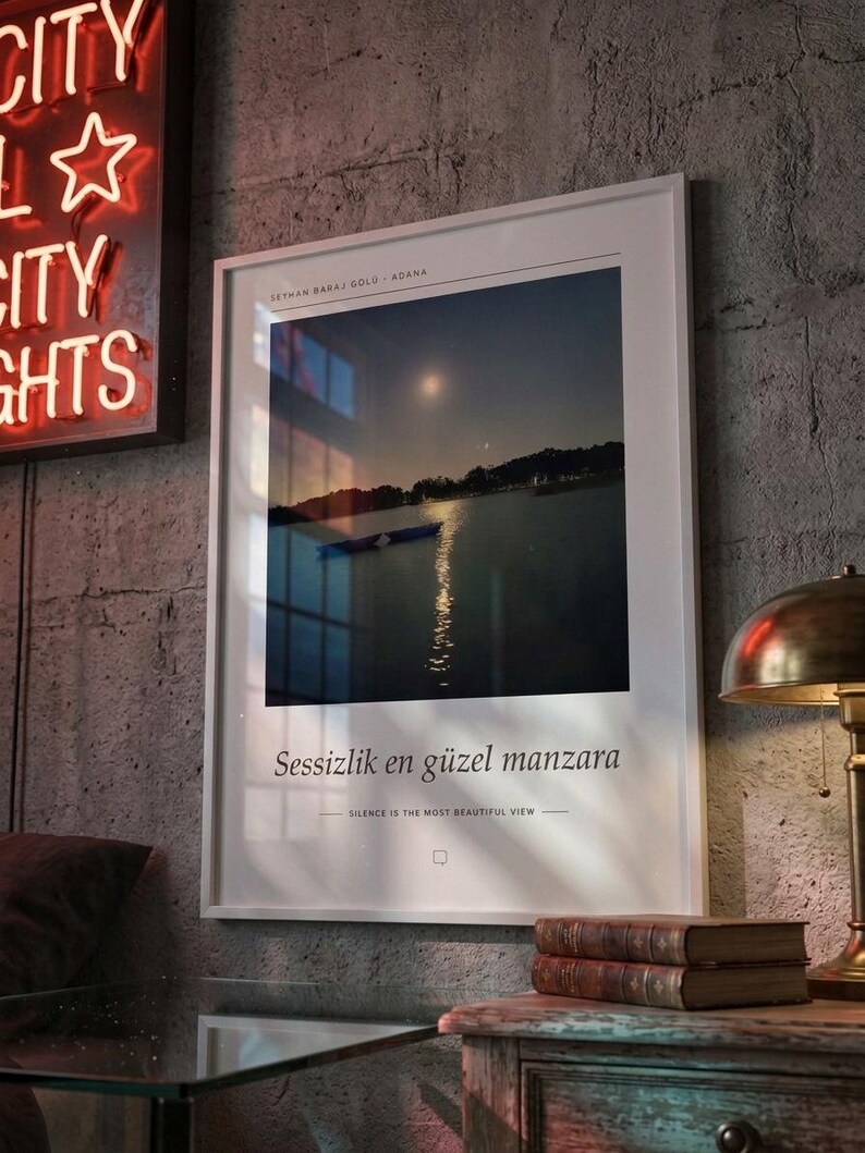 Puede incluir: Una l&aacute;mina enmarcada con un paisaje nocturno de un lago con un peque&ntilde;o bote y el reflejo de la luna. El texto dice SEYHAN BARAJ GOLU ADANA, Sessizlik en g&uuml;zel manzara y SILENCE IS THE MOST BEAUTIFUL VIEW en letras negras.