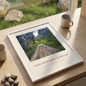 Puede incluir: Una impresi&oacute;n art&iacute;stica enmarcada en blanco con una fotograf&iacute;a de un sendero forestal. El texto dice: YAŞAR KEMAL Y&Uuml;R&Uuml;Y&Uuml;Ş PARKURU ADANA, Yeşilin i&ccedil;inde kaybol, kendini bul y LOSE YOURSELF IN THE GREEN, FIND YOURSELF. La impresi&oacute;n est&aacute; sobre una superficie de madera.