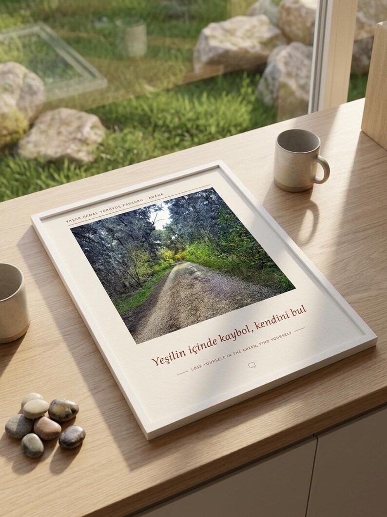 Puede incluir: Una impresi&oacute;n art&iacute;stica enmarcada en blanco con una fotograf&iacute;a de un sendero forestal. El texto dice: YAŞAR KEMAL Y&Uuml;R&Uuml;Y&Uuml;Ş PARKURU ADANA, Yeşilin i&ccedil;inde kaybol, kendini bul y LOSE YOURSELF IN THE GREEN, FIND YOURSELF. La impresi&oacute;n est&aacute; sobre una superficie de madera.