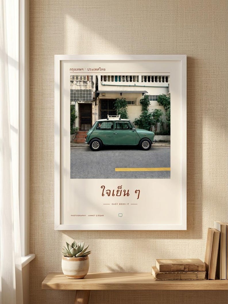 Pode incluir: Uma impress&atilde;o de arte emoldurada apresentando um Mini Cooper vintage verde-s&aacute;lvia estacionado em uma rua em Bangkok, Tail&acirc;ndia. A impress&atilde;o inclui o texto tailand&ecirc;s "กรุงเทพฯ &middot; ประเทศไทย" no topo e "ใจเย็น ๆ" com a tradu&ccedil;&atilde;o em ingl&ecirc;s "EASY DOES IT" abaixo da imagem.