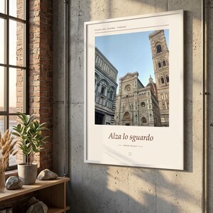 Puede incluir: Un cuadro rectangular con marco blanco que muestra una fotograf&iacute;a de la Piazza del Duomo en Florencia, Italia. La impresi&oacute;n incluye el texto "PIAZZA DEL DUOMO FIRENZE" en la parte superior y "Alza lo sguardo" con "BASINI BALDINI" debajo.