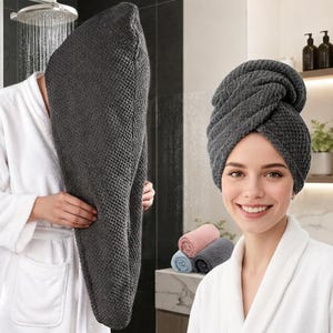 Pode incluir: Uma toalha de cabelo cinza-escura com um padrão de tecido waffle texturizado. A toalha é mostrada em dois estados: uma vez drapeada sobre a cabeça e segurada pelas mãos, e outra enrolada firmemente ao redor da cabeça. O tecido é macio e espesso.