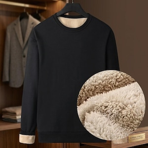 May include: A black long-sleeve sweatshirt with a crew neckline and a thick, beige faux-shearling fleece lining. The garment features ribbed cuffs that reveal the interior beige fleece material, and a circular inset showing the textured lining.
