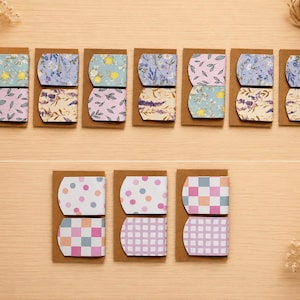 May include: Ten sets of magnetic bookmarks mounted on brown cardstock. Group A features seven sets with floral, lemon, and leaf patterns in blue, yellow, and purple. Group B features three sets with polka dot, checkered, and plaid patterns in pink and blue.