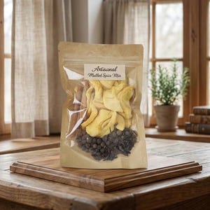 May include: A stand-up kraft paper pouch with a clear front window containing a mulled spice mix. The label reads Artisanal Mulled Spice Mix. Visible ingredients include dried yellow apple slices, brown cinnamon sticks, and dark whole spices.