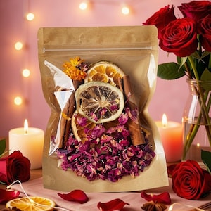May include: A clear plastic pouch with a brown paper backing containing a mixture of dried pink rose petals, sliced citrus fruits, cinnamon sticks, and yellow marigold flowers. The pouch is sealed at the top and displays the botanical contents.