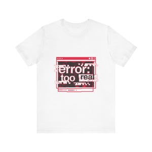 May include: A white short-sleeve t-shirt featuring a central red graphic of a computer window frame. Inside the frame is a black background with the white text "error: too real" displayed in a distorted, digital glitch style with red accents.