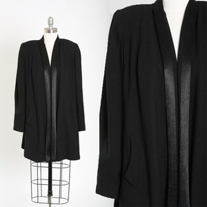May include: A black long-sleeved jacket with a shawl collar and a satin trim down the front.
