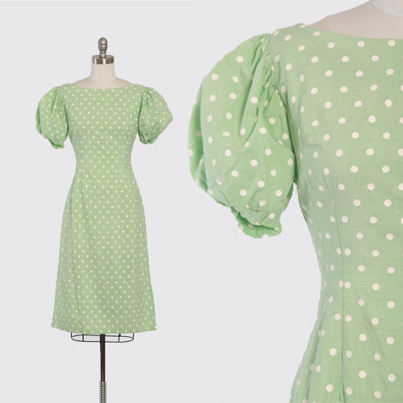 May include: A green dress with white polka dots and puffed sleeves. The dress has a fitted bodice and a slightly flared skirt.