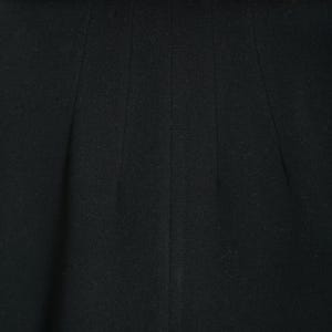 May include: A black coat with a brown fur collar. The coat has a simple design with vertical seams. The fur collar is a rich brown color and adds a touch of luxury to the garment. The coat appears to be made of a soft, warm material.
