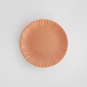 May include: A peach-colored ceramic plate with a swirl design.