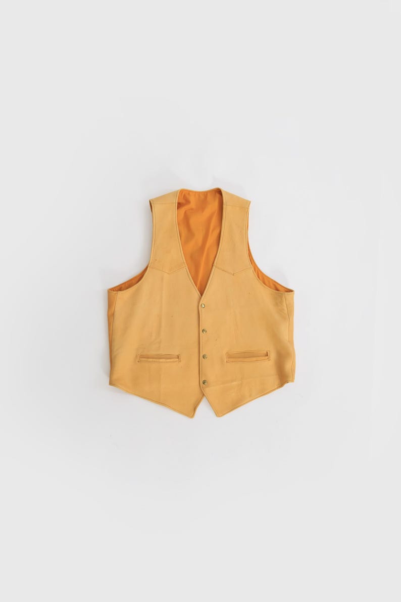 May include: A yellow suede vest with a button-up front and two pockets. The vest has a contrasting orange lining.