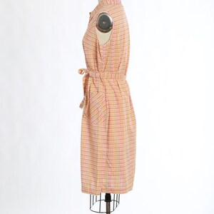 May include: A pink and green checked sleeveless dress with a tie belt and a pocket on the side.