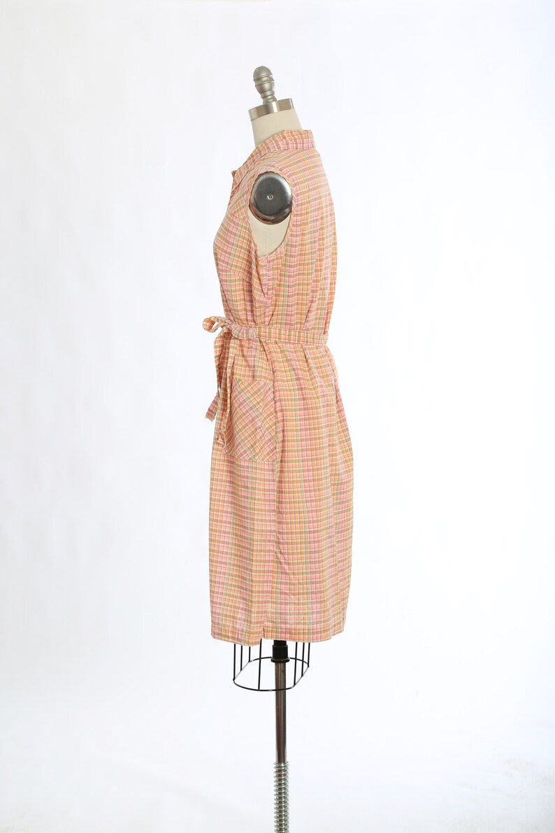 May include: A pink and green checked sleeveless dress with a tie belt and a pocket on the side.